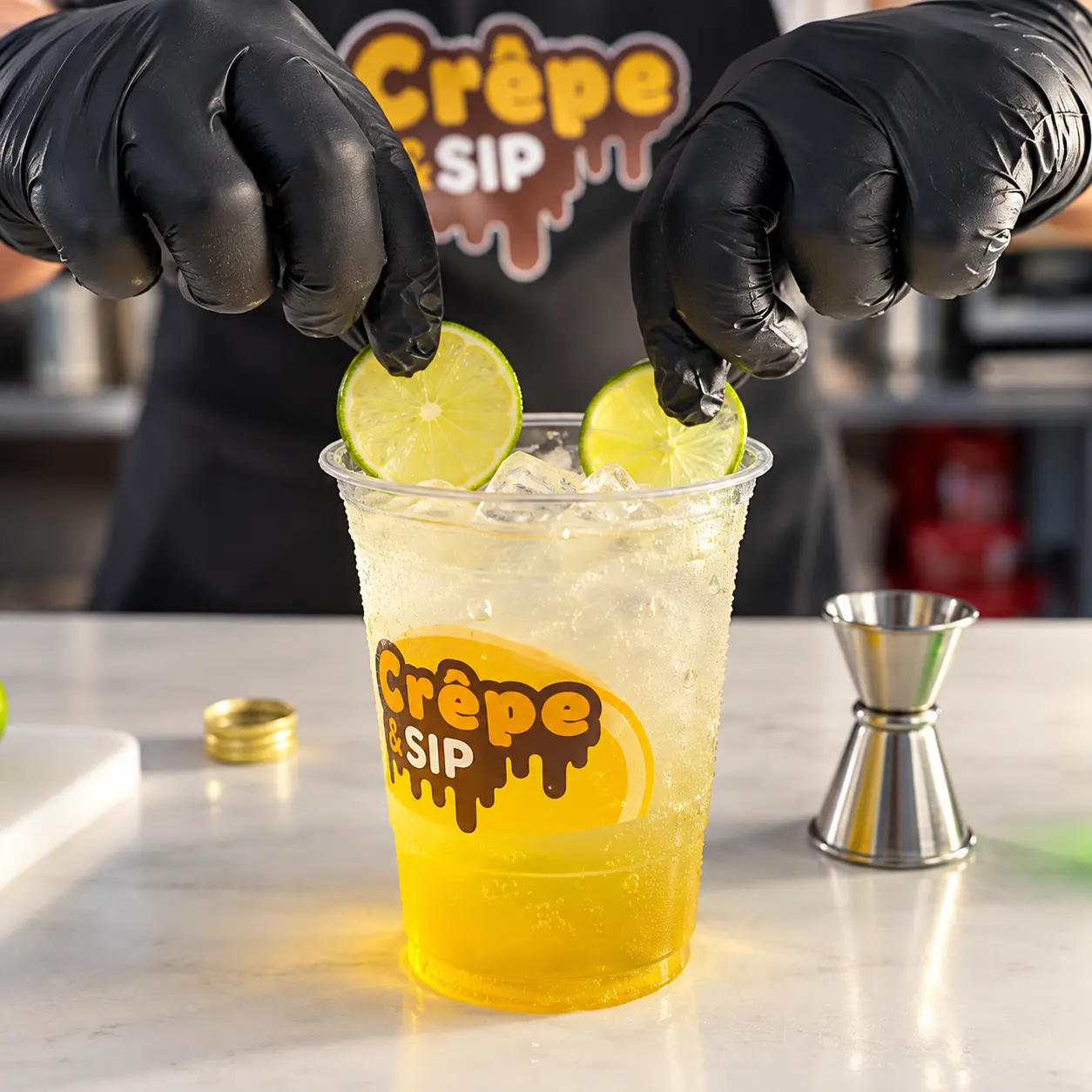 Lime slices added to a yellow mojito in a Crêpe & Sip cup