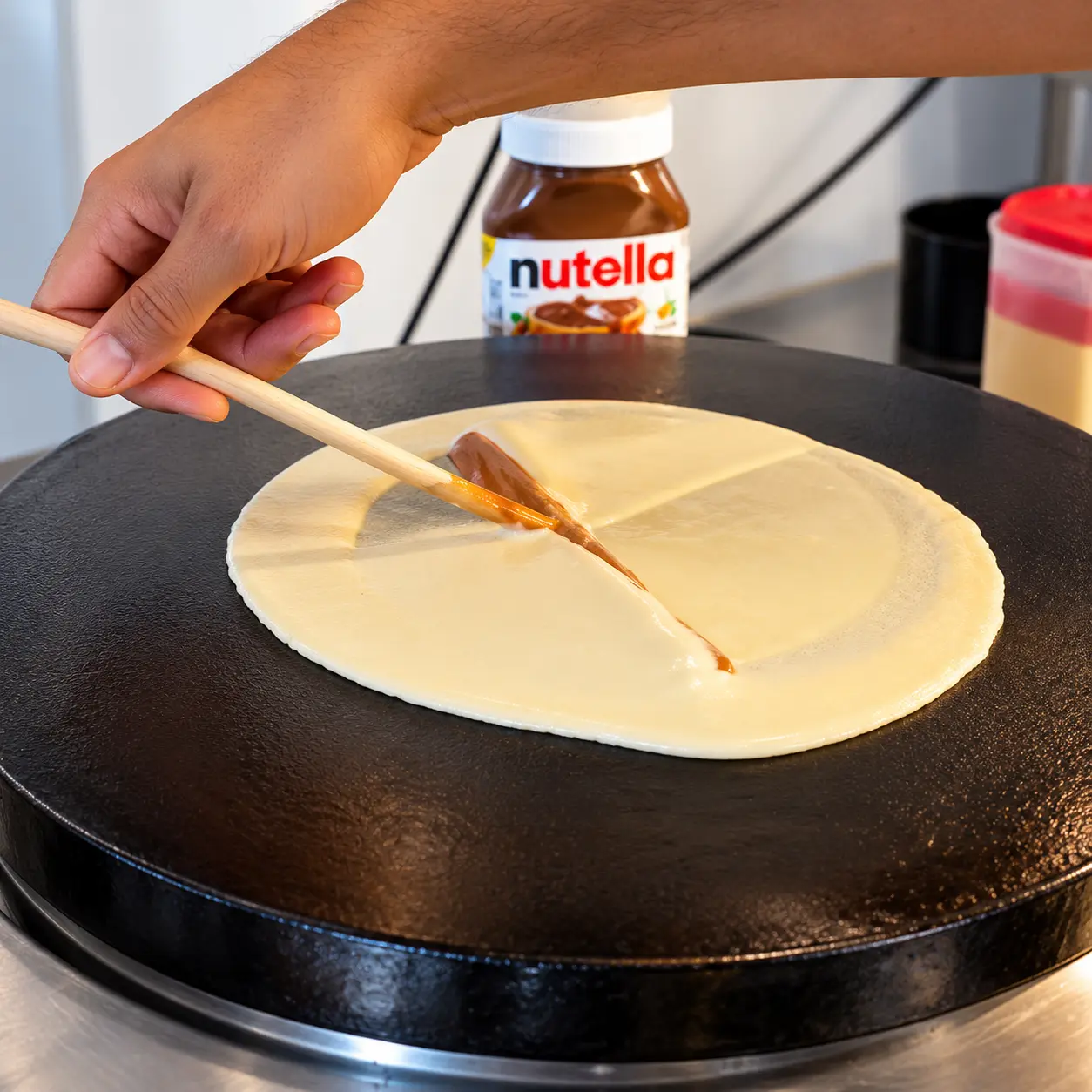 Crêpe batter being spread on a hot griddle