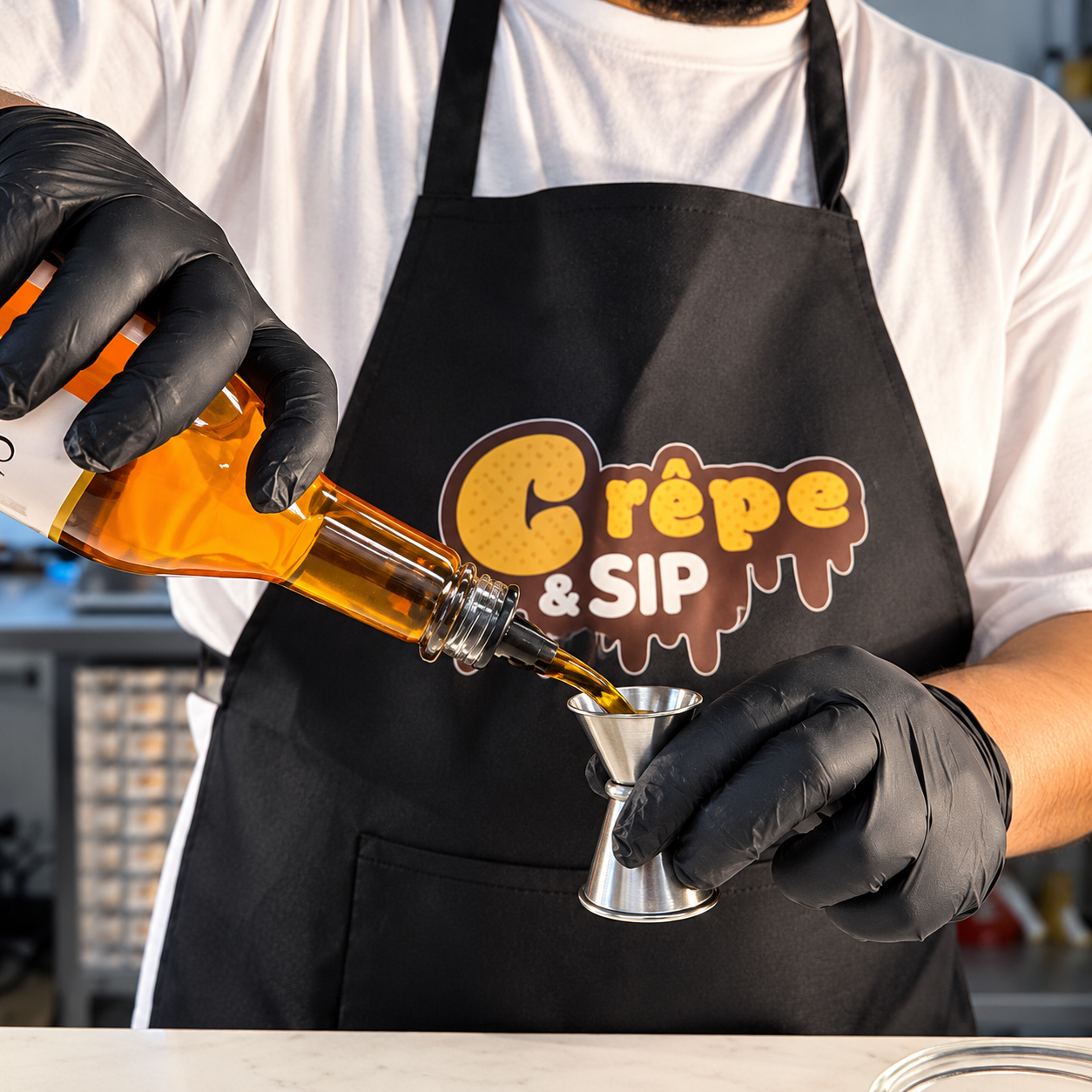 Team member in a Crêpe & Sip apron pouring syrup behind the counter