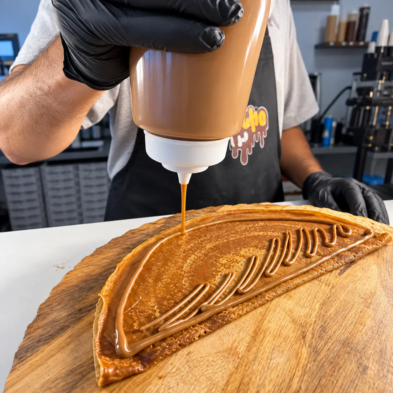Sauce being drizzled over a folded crêpe